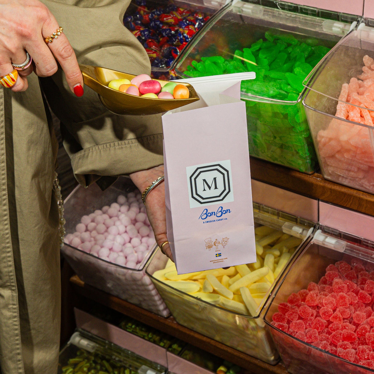 A candy bag with a custom monogram sticker held over bins of candy